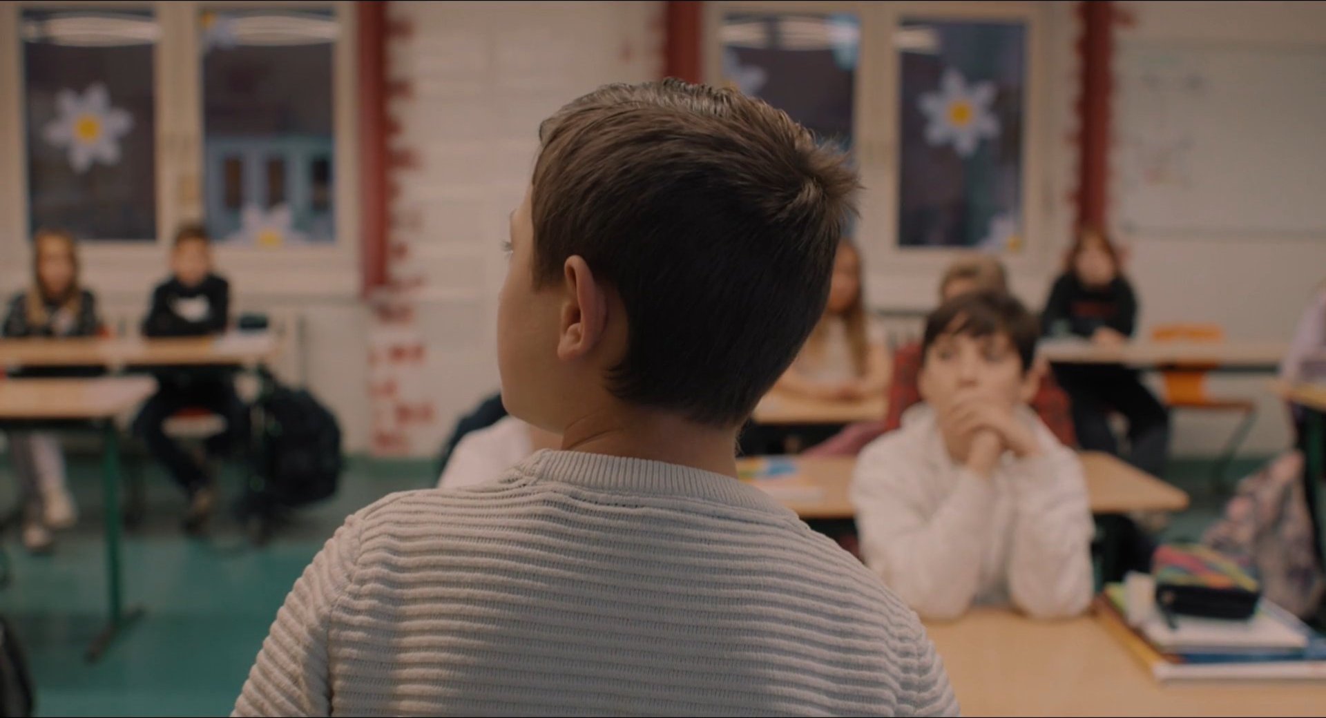 Filmbild aus dem Film ZIRKUSKIND zeigt Santino mit dem Rücken zu Kamera vor einer Schulklasse stehend