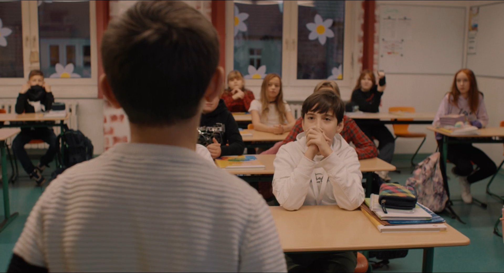 Filmbild aus dem Film ZIRKUSKIND zeigt Santino mit dem Rücken zur Kamera vor einer Schulklasse stehend