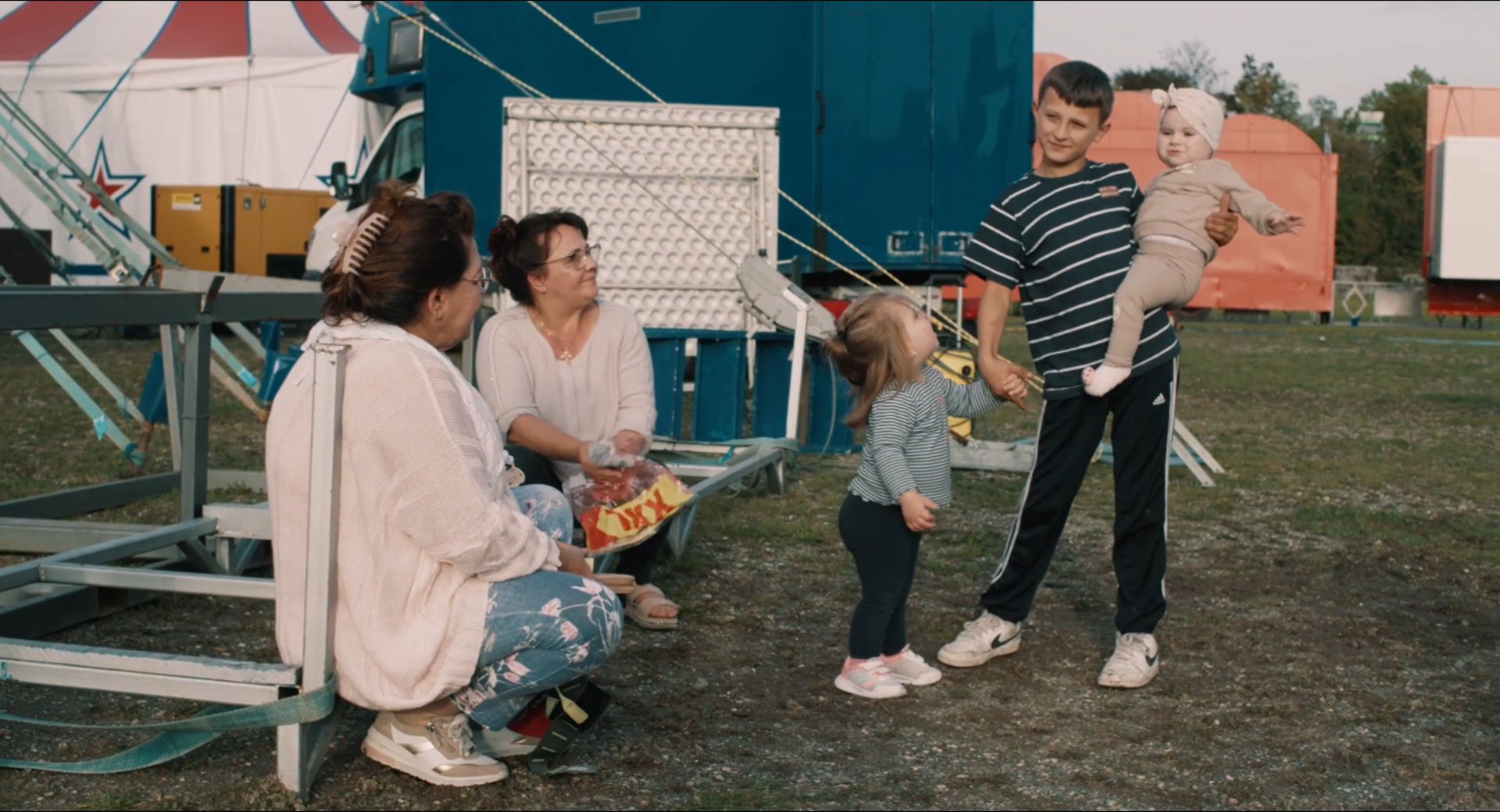 Filmbild aus dem Film ZIRKUSKIND zeigt Santino mit Verwandten ein Kleinkind auf dem Arm, ein weiteres an der Hand