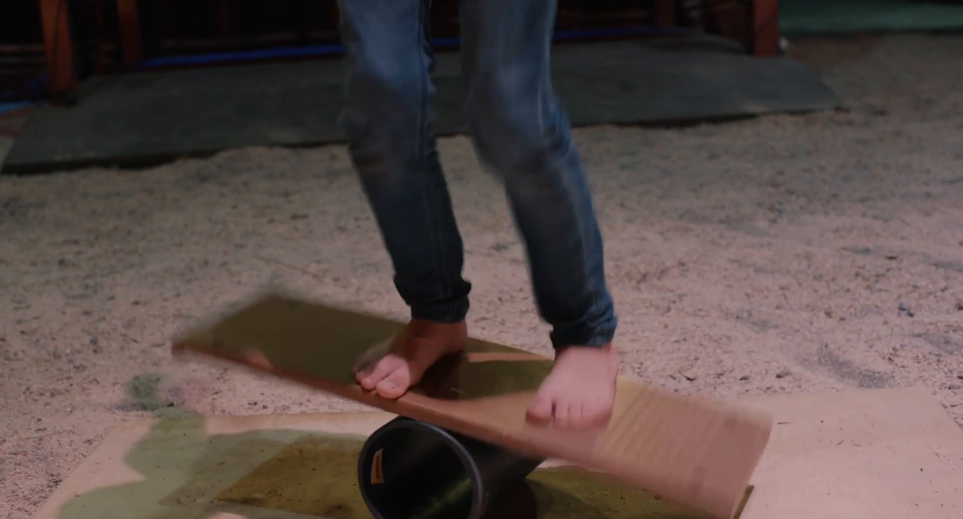 Filmbild aus dem Film ZIRKUSKIND zeigt Santino mit einem Brett auf einer Metallrolle balancieren